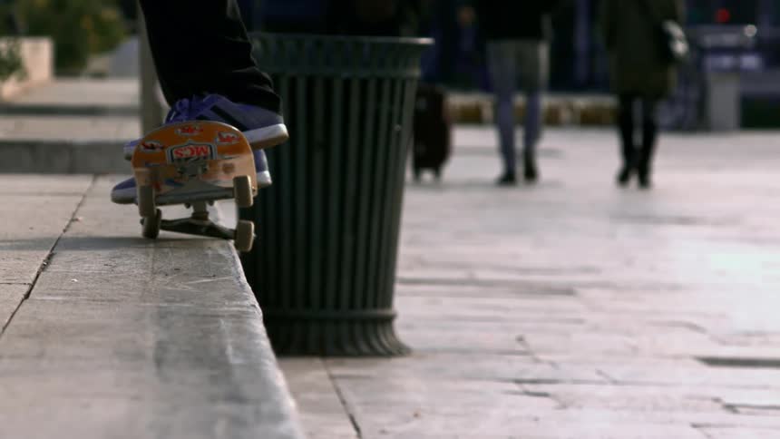 Skate boarder skates across concrete step outdoors
