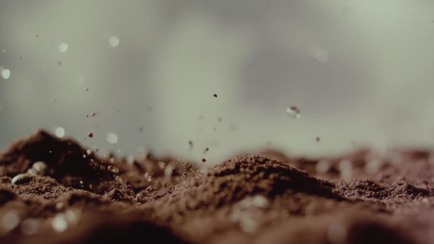 Drops of water falling onto coffee grounds in slow motion