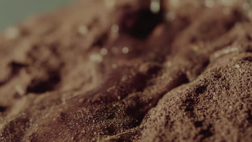 Water flowing over brown powder in slow motion