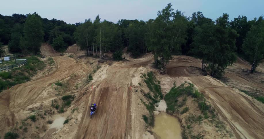 Motocross rider takes jump on course near woods