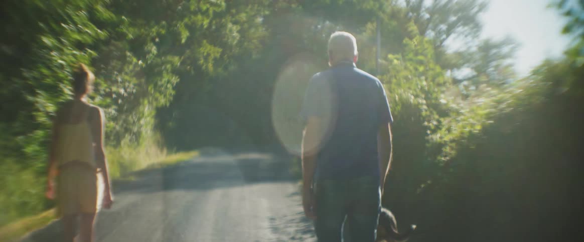 A man and a woman walking in nature with a dog