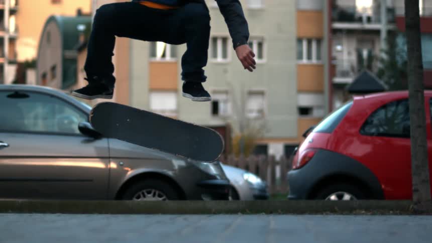 Person performing a skateboard trick on a sidewalk beside the street