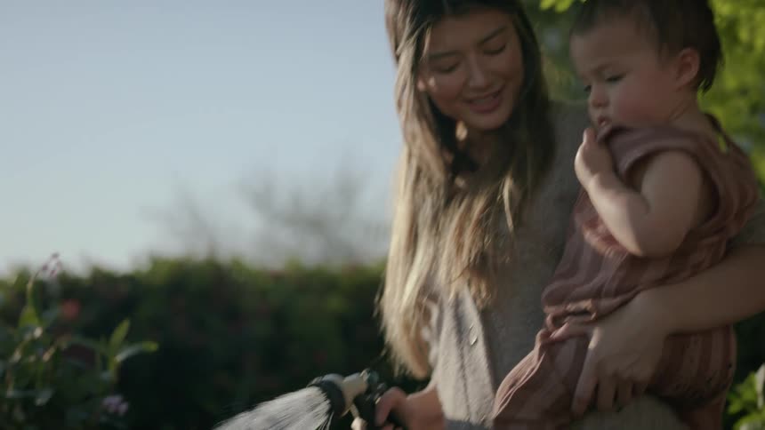 Mother holding her daughter while cutting vegetables