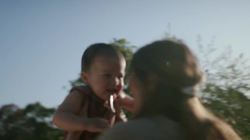 Mother holding her young daughter spinning around both smiling widely