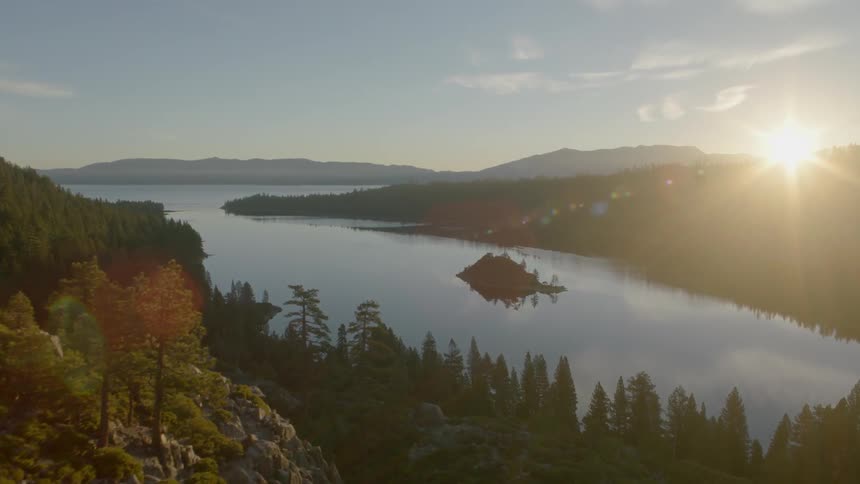 Skimming low along a rock face to reveal Emerald Bay as the sun crests above the horizon