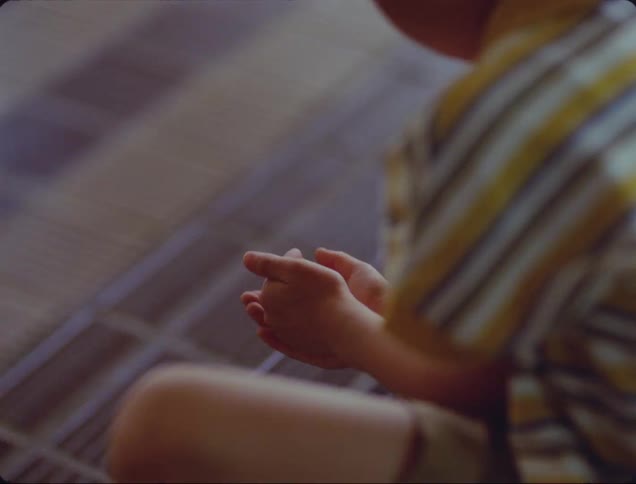 Boy plays with small sphere ball while sitting indoors