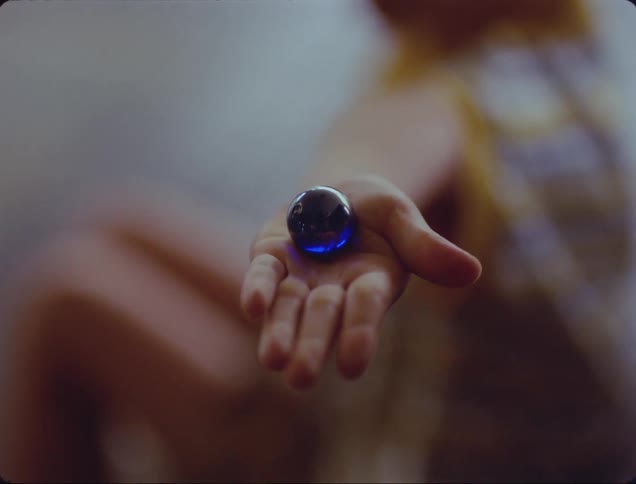 A person opens their hand to show a blue marble