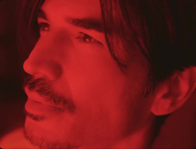 Close up of the face of a man under red lights