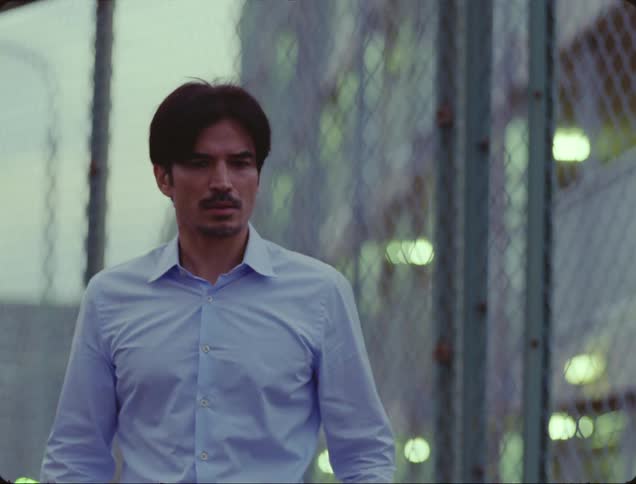 A man stands outside looking confused as another man passes by