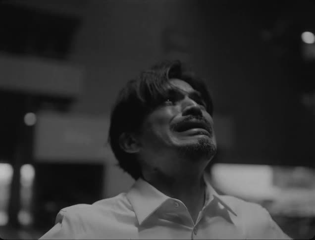 A man in a white shirt crying indoor