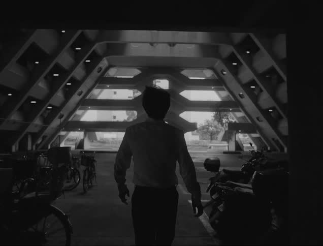 A man walking in the garage and also starring up at the ceiling