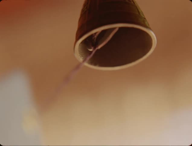 Closeup of a bell with a hanging rope from the ceiling in motion