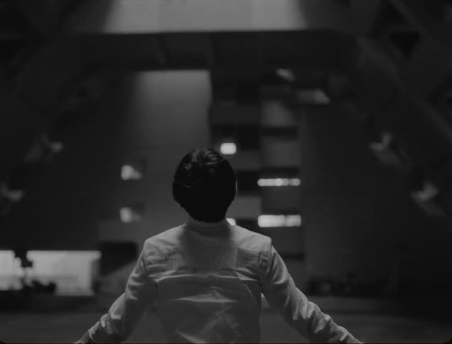 Crying man stands with out stretched arms under sloping walls of building