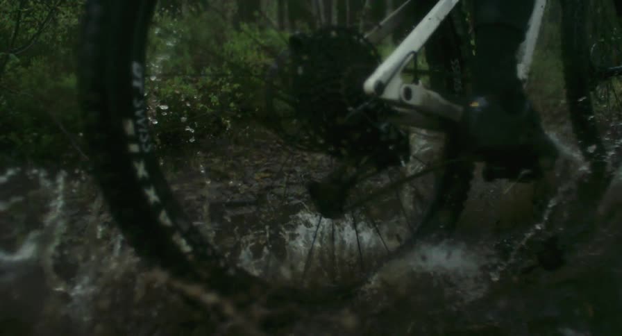 Closeup of bicycle wheels passing through a puddle of water in the midst of nature