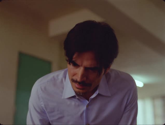 A man with a mustache is approaching something he is looking at worriedly