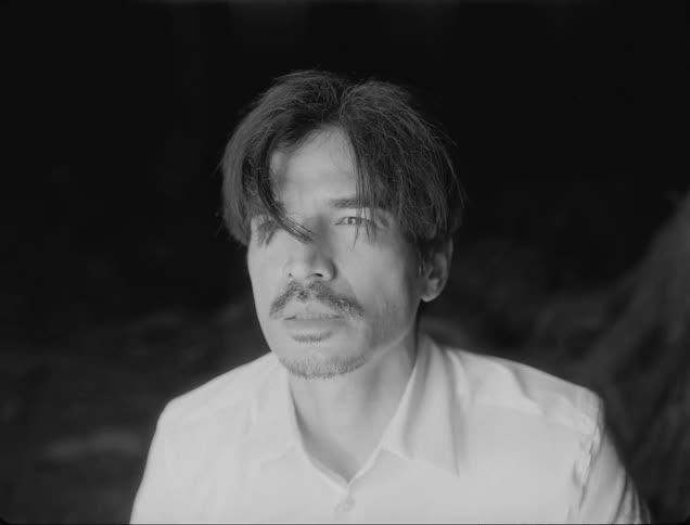 A man looks up as an lightemitting hand reaches for his face