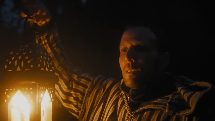 A man is carrying a lantern as he walks at night