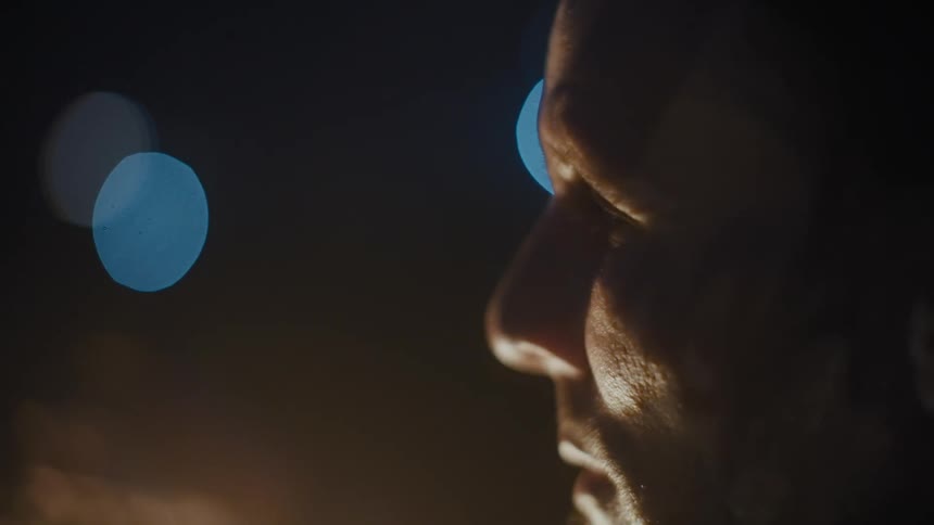 A face of a man who is looking at holes in the wall with blue lights