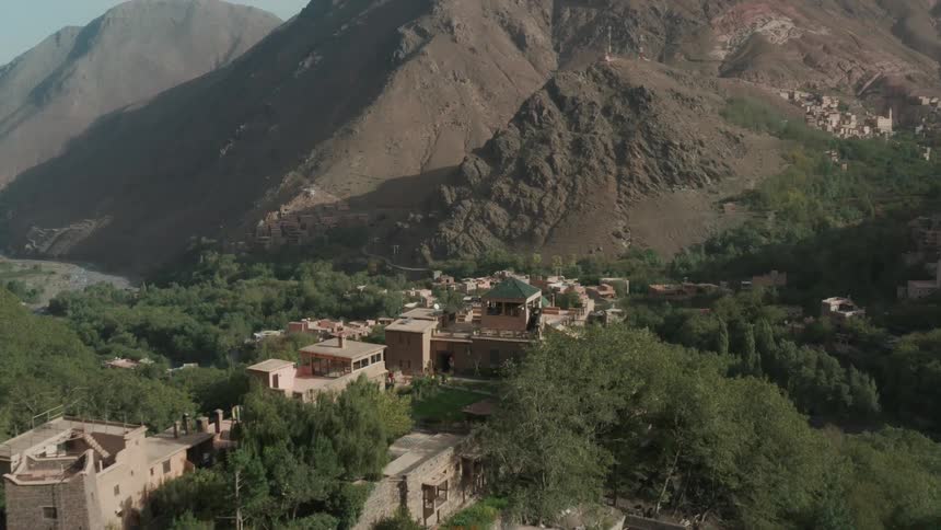 Aerial view of a village in a river valley near a large mountain