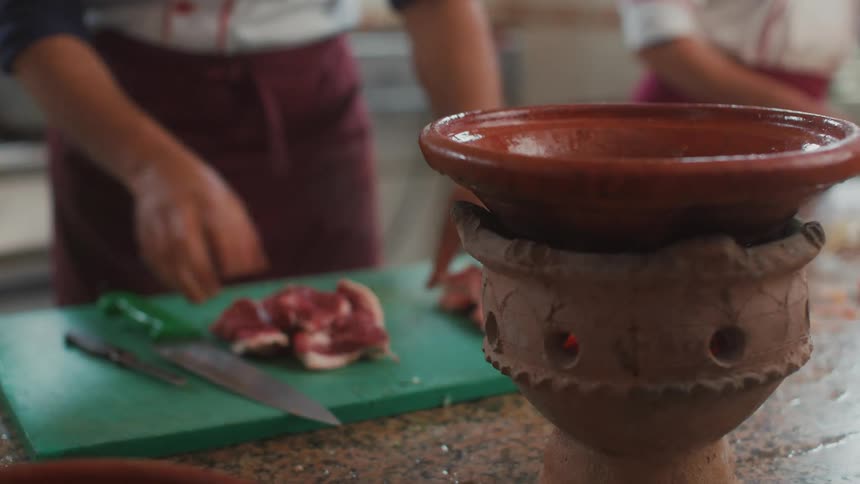 Two women cutting meat and placing it into a bowl
