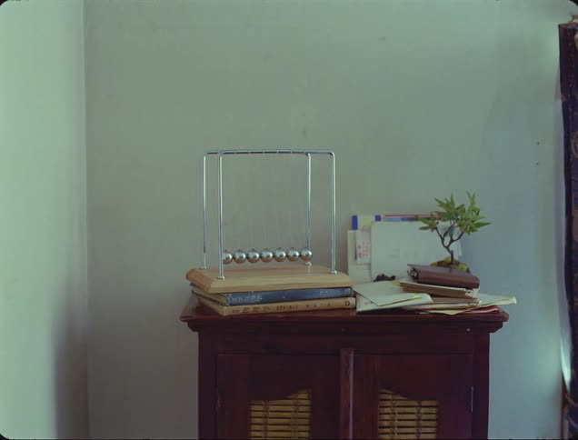 Man exits a room with a ball clicker toy resting over a table