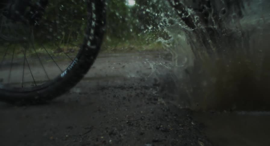 Closeup of the wheels of a mountain bike passing through a puddle of water