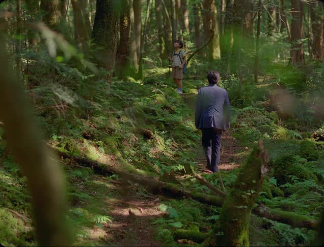 Father and son move along narrow trail through woods