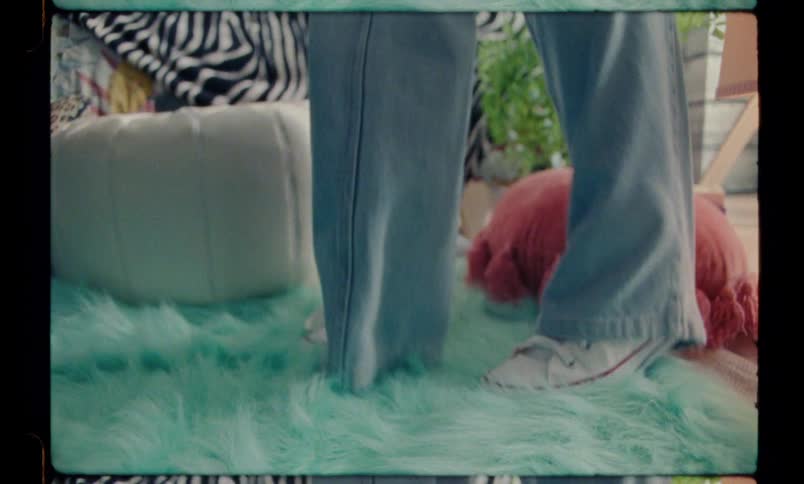 Young person puts jeans on and falls over a colorful carpet