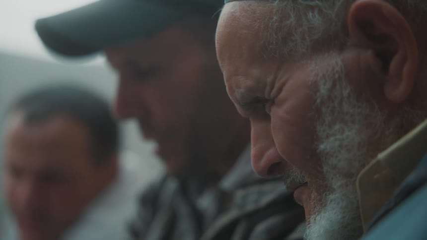 Portrait of an elderly man and two other men looking intently at something and having a conversation