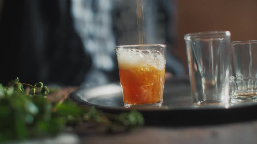 Man pours a hot beverage into a glass cup