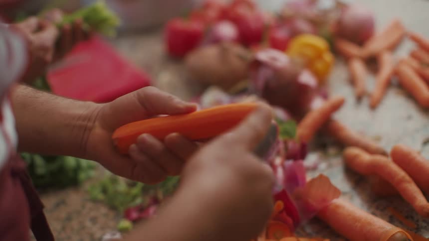 A close up clip of a person pealing carrot vegetable