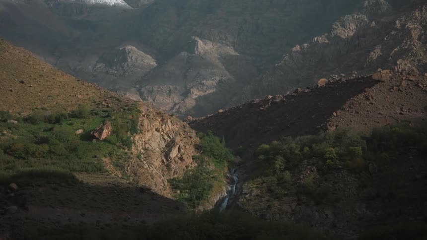 A mountain range with snowcapped peaks rocky terrain in the foreground