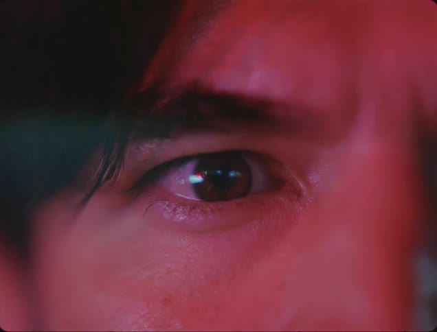 The reflection of a blinking traffic light can be seen in a mans eye