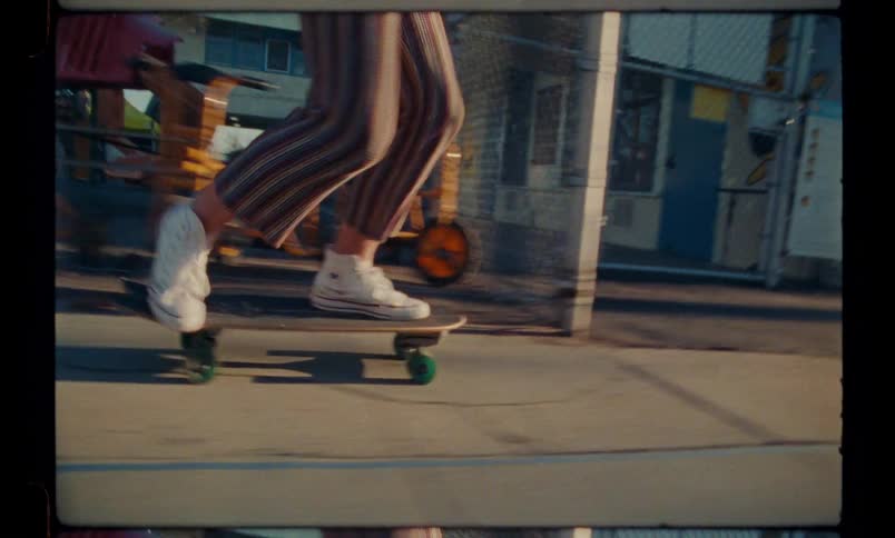 Closeup of the feet and legs of a person skateboarding on the sidewalk