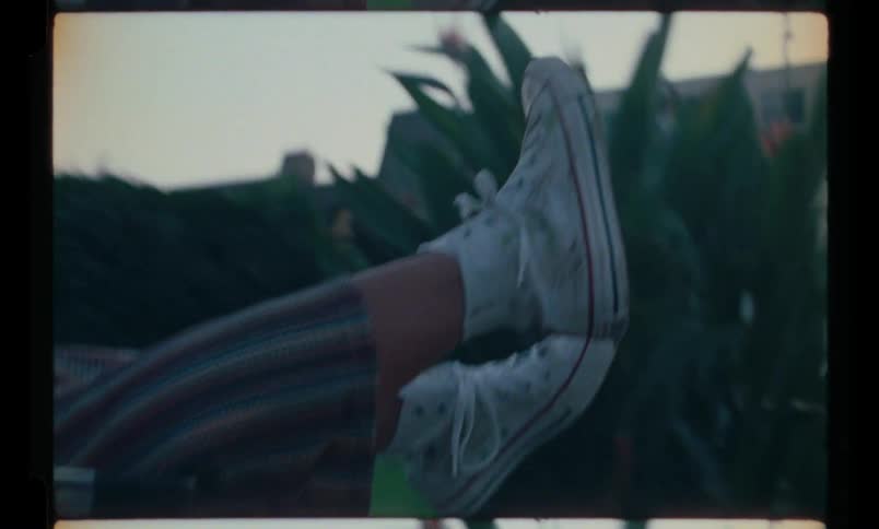 View of the legs of some teenagers being pushed in a shopping cart on the sidewalk