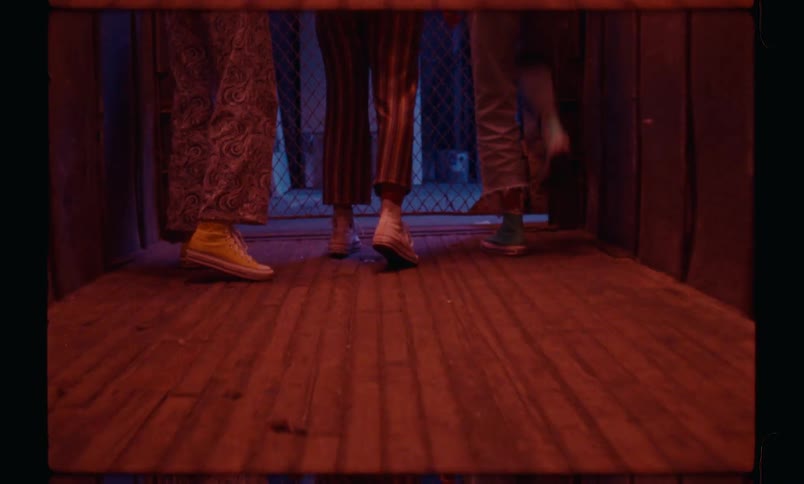 Legs of three females getting out of a wooden elevator at night