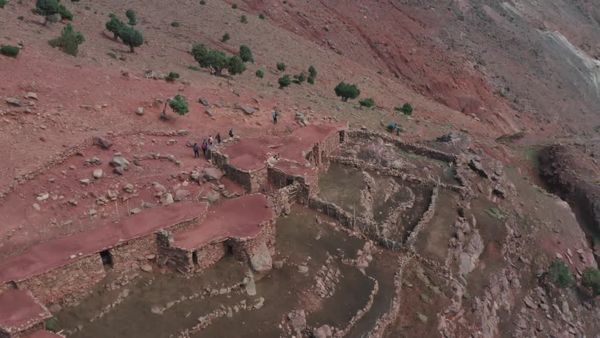 Aerial of a group of travelers walking past an ancient civilization set in a mountainous region
