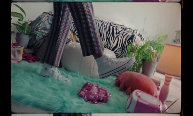 A person standing over a colorful carpet playfully kicks a pompom