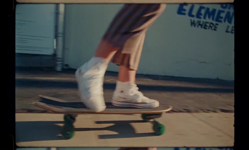 Closeup of a person on a skateboard performing simple tricks on a sidewalk in the street