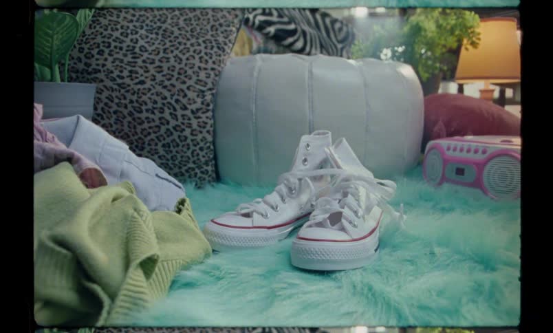 A pair of white sneakers falling onto a blue shag rug