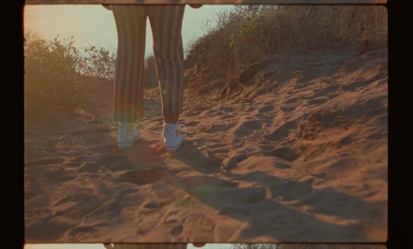 Legs of a lady walking towards the sea at sunset