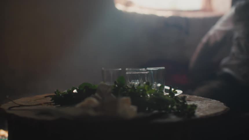 A person sits and slaps their knee as empty glassware is nearby