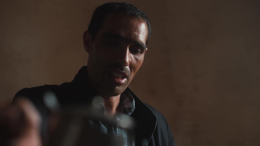 A man with a sweaty face is spilling water from a teapot