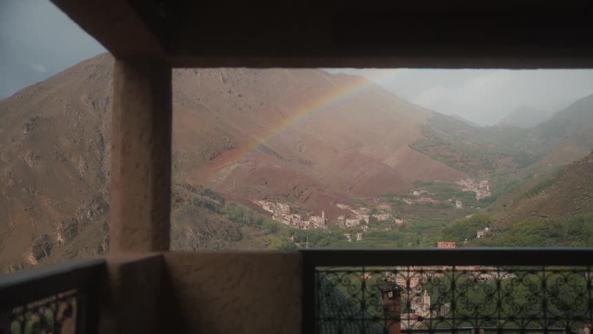 Rainbow over mountain and green valley landscape seen from balcony