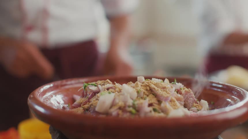A chef is seasoning a dish