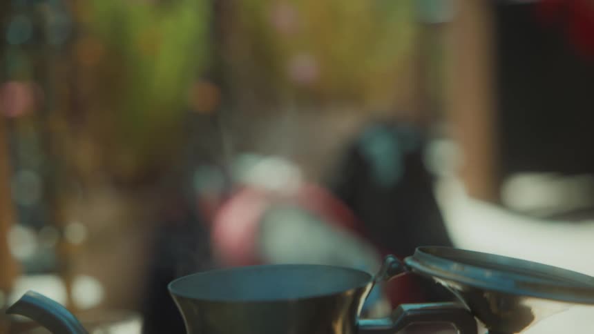 Closeup of a kettle pouring hot water into another container