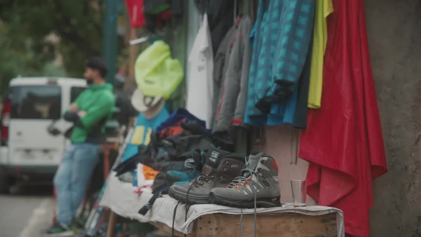Shoes and cloths hanged on the wall outside at midday