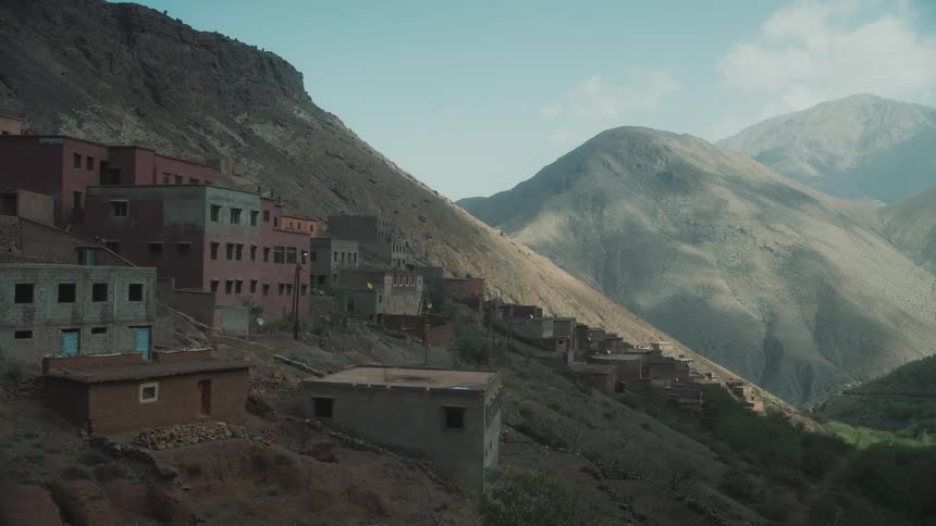 Houses dotting a barren mountain slope landscape