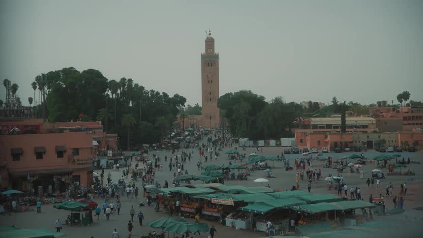 A place with a commercial market with lots of people and behind a large tower