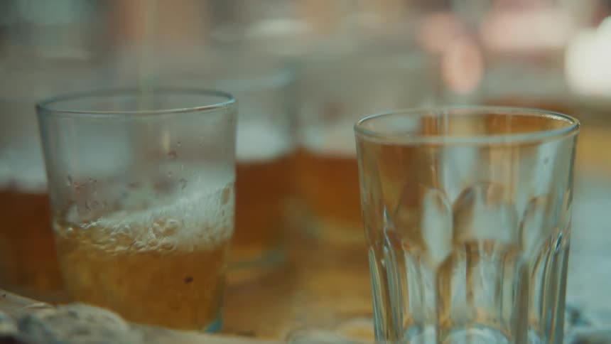 Tea being poured into a closeup of glasses